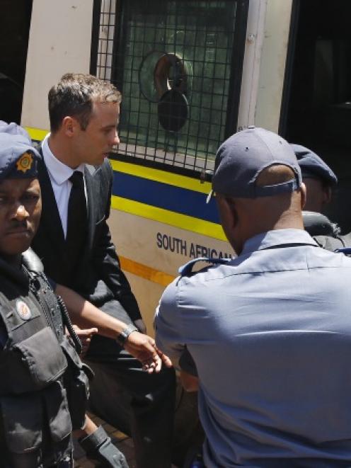 South African Olympic and Paralympic sprinter Oscar Pistorius (centre) enters a police van after...