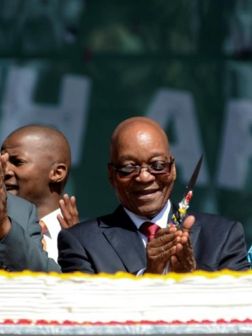 South African President Jacob Zuma (C) cuts a cake as crowds gather to celebrate Freedom Day at...