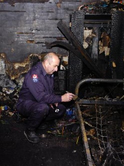 Southern region fire safety officer Stuart Ide examines the charred remains of a bedroom at a...