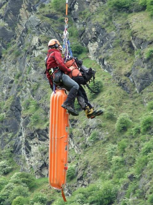 Specialist rescuers are lifted by helicopter on to a Queenstown cliff face as part of a training...