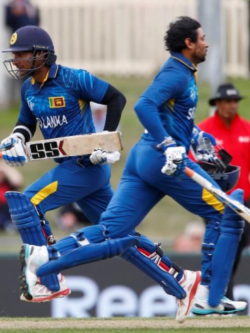 Sri Lankan batsmen Tillakaratne Dilshan (R) and Kumar Sangakkara cross while running during their...