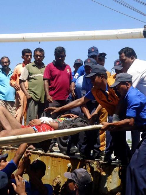 Sri Lankan navy soldiers carry an injured man as part of a rescue of 32 Myanmar nationals who...