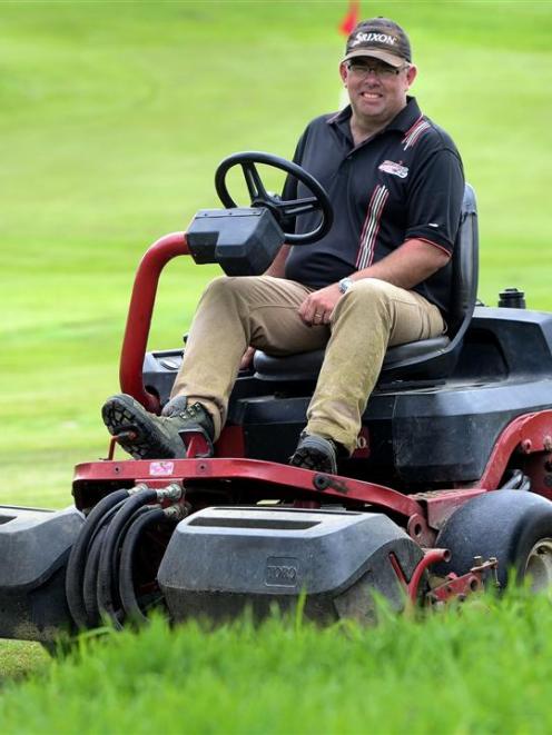 St Clair green keeper Andrew Hobbs relaxes on his mower in front of the new 18th green yesterday....