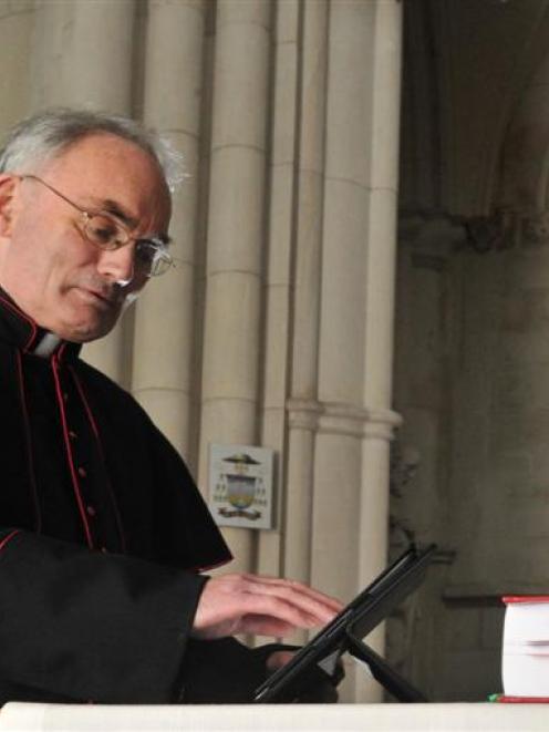 St Joseph's Cathedral priest Monsignor John Harrison accesses material on an iPad lying next to...
