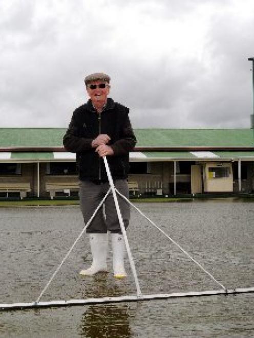 St Kilda Bowling Club greenkeeper Russell Geeves sweeps water from one of the club's greens after...