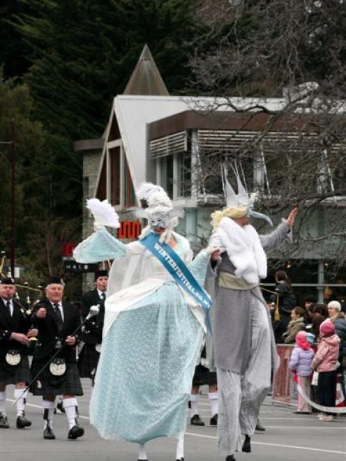 Stiltwalkers wave to the crowd gathered for the Queenstown Winter Festival Street Parade on...