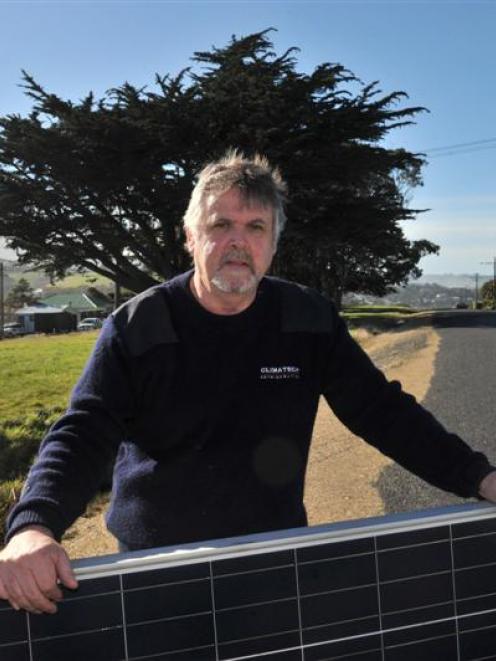 Stu Nicholson holds a solar panel set  to be installed on the roof of his Brighton home, which is...