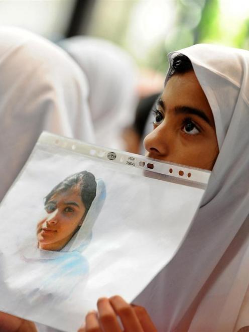 Students hold pictures of schoolgirl Malala Yousufzai, who was shot by the Taliban, during a...