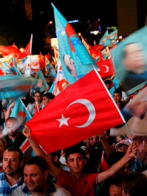 Supporters of Turkey's Prime Minister Tayyip Erdogan celebrate his election victory in front of...