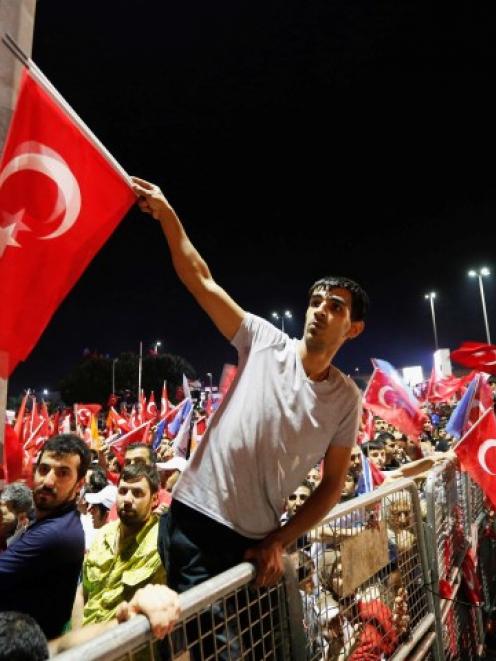 Supporters of Turkish Prime Minister Tayyip Erdogan shout slogans as they wait for his return at...