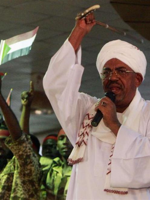 Supporters wave Sudanese flags as Sudan's President Omar al-Bashir addresses them  during a rally...
