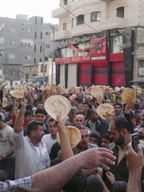 Syrian men carry bread loaves during a protest against Syrian President Bashar Assad's regime, in...