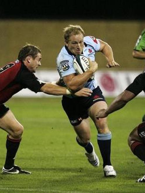 Waratahs halfback Brett Sheehan tries to beat the tackles of Crusaders halfback Andy Ellis (left)...