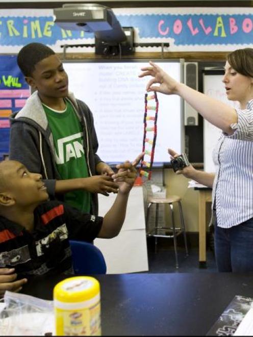 Teacher Leah Hirsch (right) discusses a DNA helix made out of candy with students Jahmer Millien...