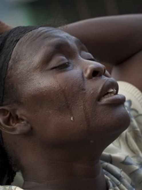 Tears run down a woman's face as she attends a group prayer in a makeshift shelter in the street...