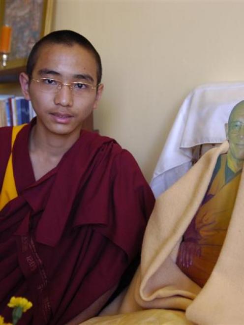 Tenzin Lhundup with a cardboard photograph of Geshe Dhargyey, founder of the Dhargyey Buddhist...