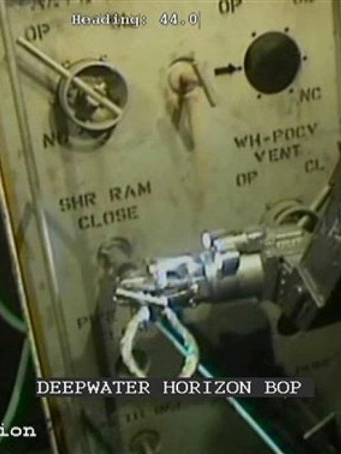 The arm of a robot submarine is shown attempting to activate a shutoff device known as a blowout...