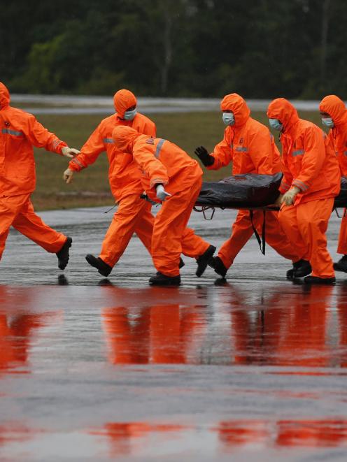 The body of an AirAsia QZ8501 passenger is carried to an ambulance from a Singapore Navy...