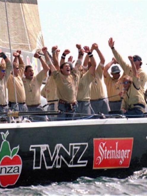 The crew members of New Zealand's Black Magic celebrate as they cross the finish line in the...
