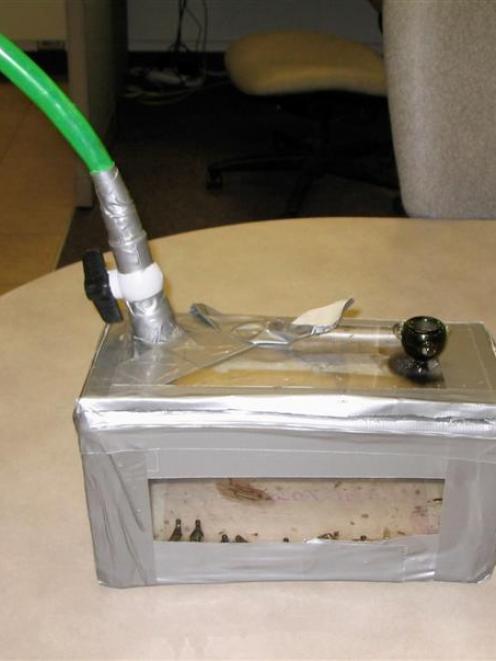 The homemade bong, consisting of a piece of garden hose attached to a duct-taped plexiglas box. ...