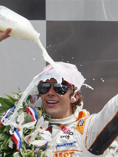 The late Dan Wheldon celebrates while pouring the traditional milk on his head after winning the...