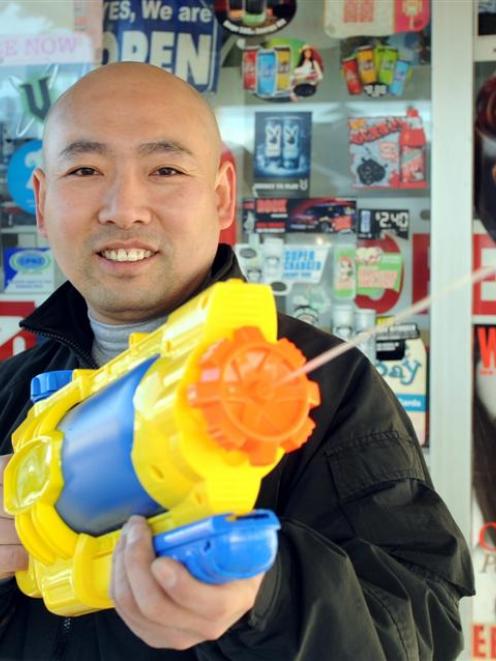 The owner of the 10 O'Clock Dairy in St Kilda, Ge Song, with the large water gun he has used to...
