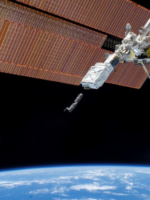 The Small Satellite Orbital Deployer, in the grasp of the Kibo laboratory robotic arm, is...