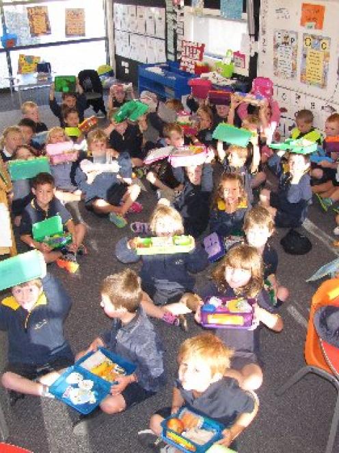 Three-quarters of this new entrants class at the Wanaka Primary School show their lunch boxes are...