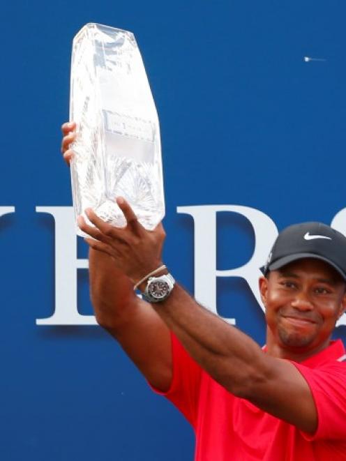 Tiger Woods holds up the trophy after winning the PGA Players Championship golf tournament at TPC...
