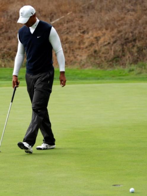 Tiger Woods reacts after missing a birdie putt at the 18th hole during the first round of the...