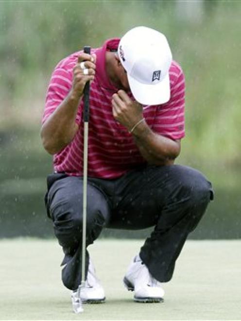 Tiger Woods waits to putt on the 16th hole during the first round of the Deutsche Bank...