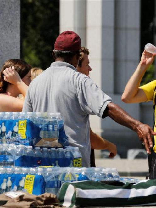 Tourists drink free water given away to help combat the heat at the National World War II...