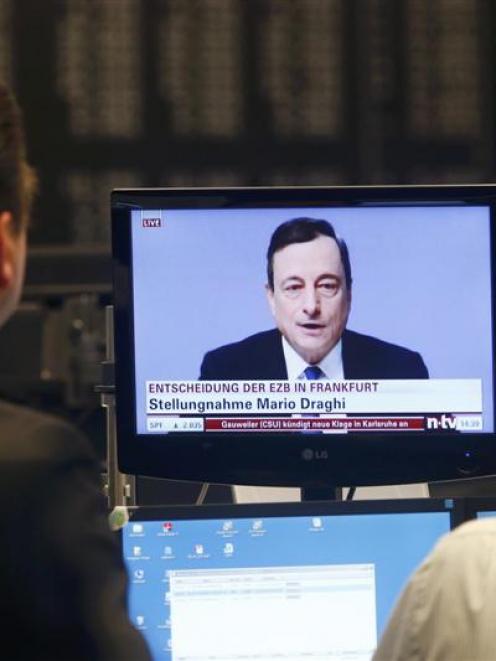 Traders watch European Central Bank president Mario Draghi make his announcement on asset buying...