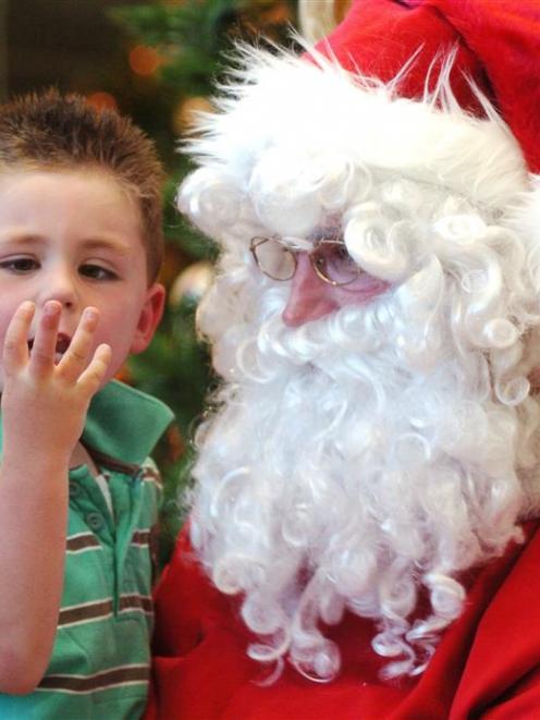 Trent Chalmers (4) of Dunedin goes through his Christmas checklist with Santa in the Golden...