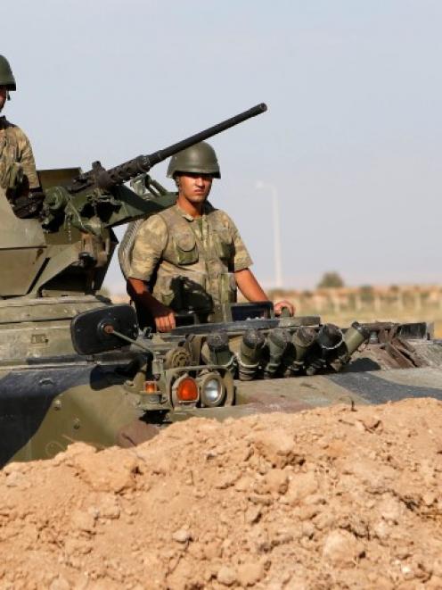 Turkish soldiers stand guard in an armoured personnel carrier on the Turkish-Syrian border near...