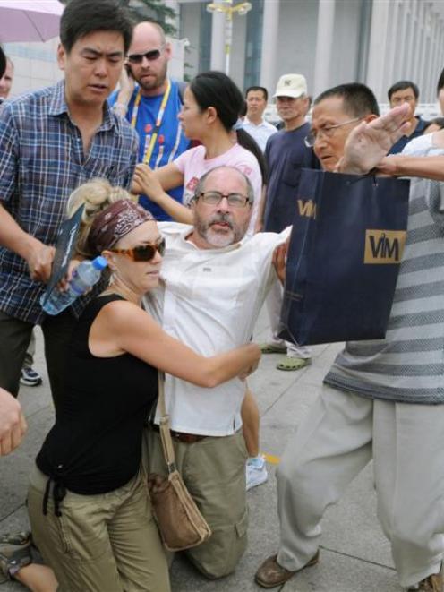 Two activists, centre, of an U.S. religious group are grabbed by security agents in Tiananmen...