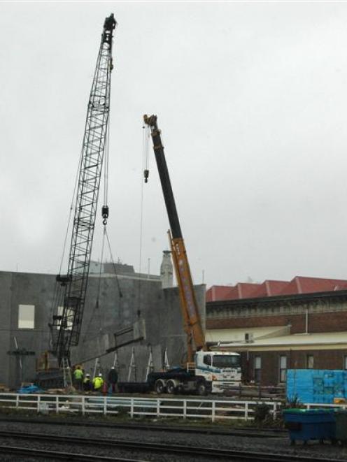 Two cranes lift an 8.5m-long concrete wall panel into place as a twin-level storage building at...