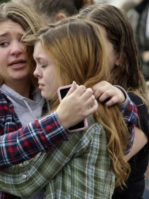 Two girls hug at Shoultes Gospel Hall church where families are reuniting after an active shooter...