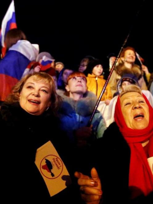 Two women hold flags reading 'Crimea is with Russia' as people wait for the announcement of...