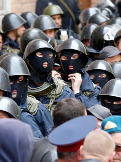 Ukrainian Interior Ministry security forces, blocked by pro-Russian activists, gather outside the...