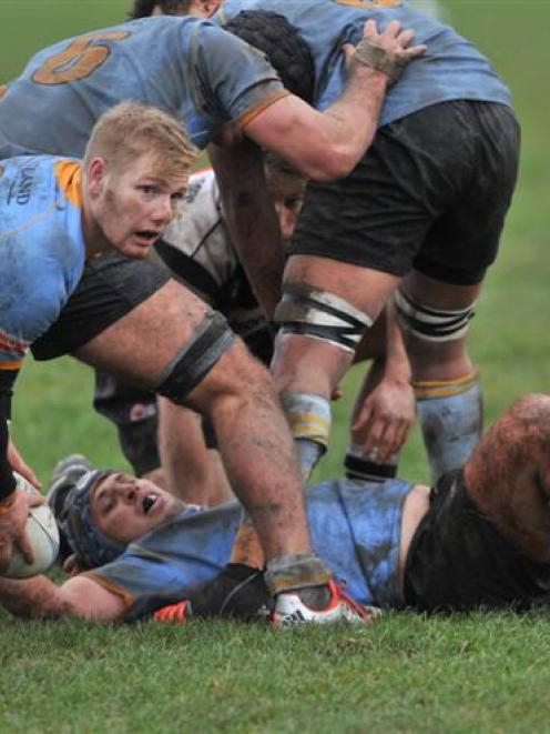University A halfback Kaide Whiting looks to move the ball on from under the feet of loose...