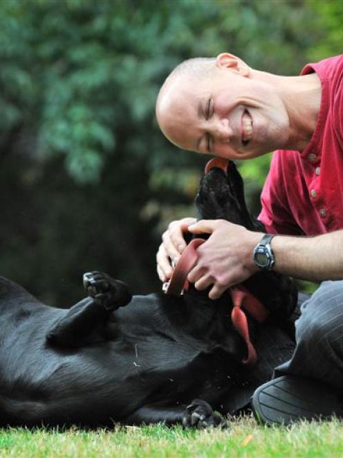 University of Otago psychology researcher Associate Prof Ted Ruffman plays with black Labrador...