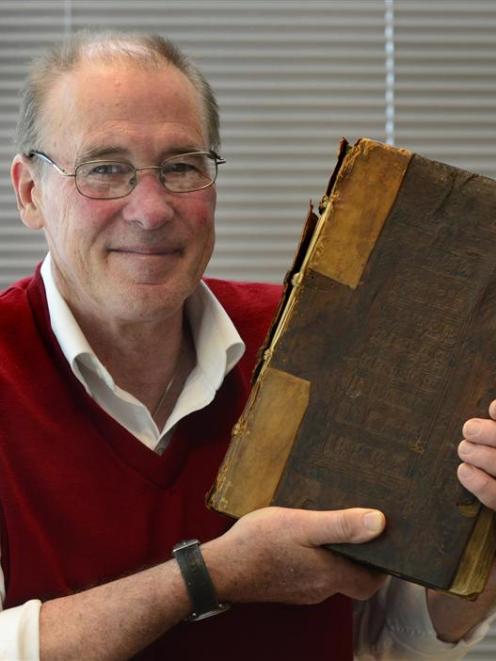University of Otago special collections librarian  Donald Kerr holds up the 15th-century book...