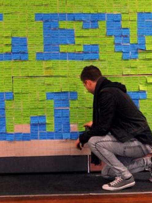 University of Otago student Ollie Wilson (25) adds his details to a student debt art installation...