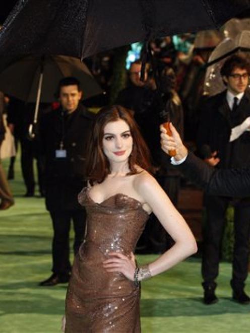 US actress Anne Hathaway, centre, is sheltered from the rain as she arrives for the Royal World...