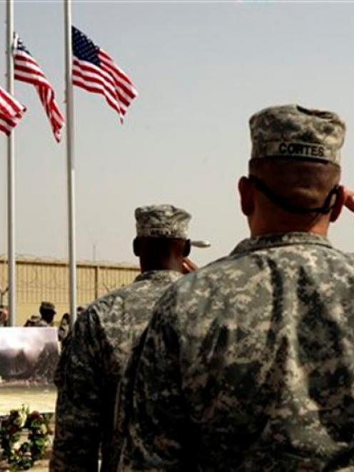 US Army soldiers salute American flags at a ceremony  at Camp Liberty in Baghdad, where a soldier...