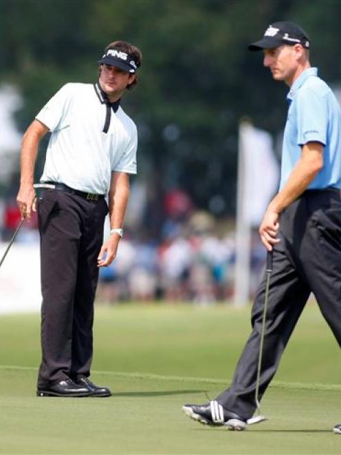 US golfer Bubba Watson (L) and his compatriot Jim Furyk watch Watson's putt on the seventh hole...