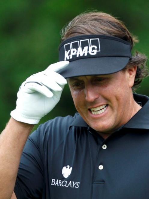 US golfer Phil Mickelson reacts to applause after hitting his tee shot on the 11th hole during...