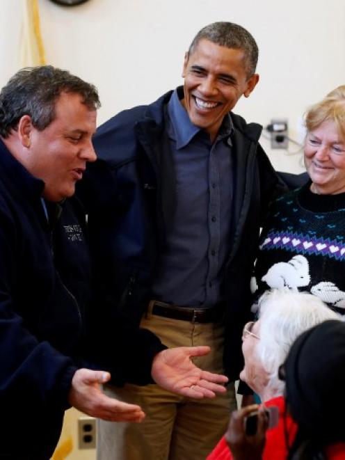 US President Barack Obama (2nd L) and New Jersey Governor Chris Christie (L) talk with survivors...