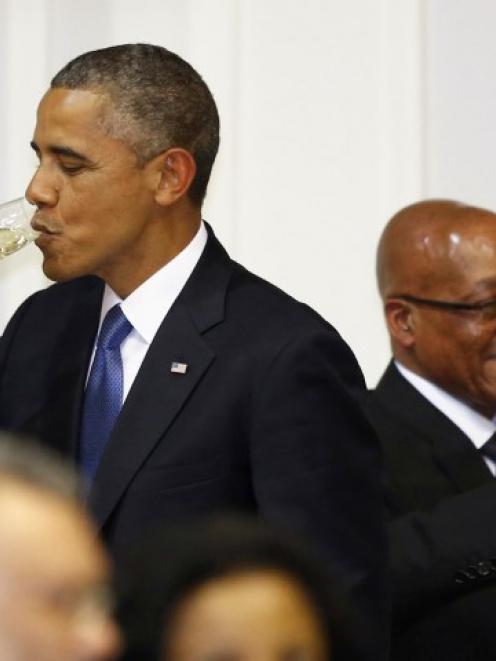 US President Barack Obama takes a drink as he attends an official dinner with South African...